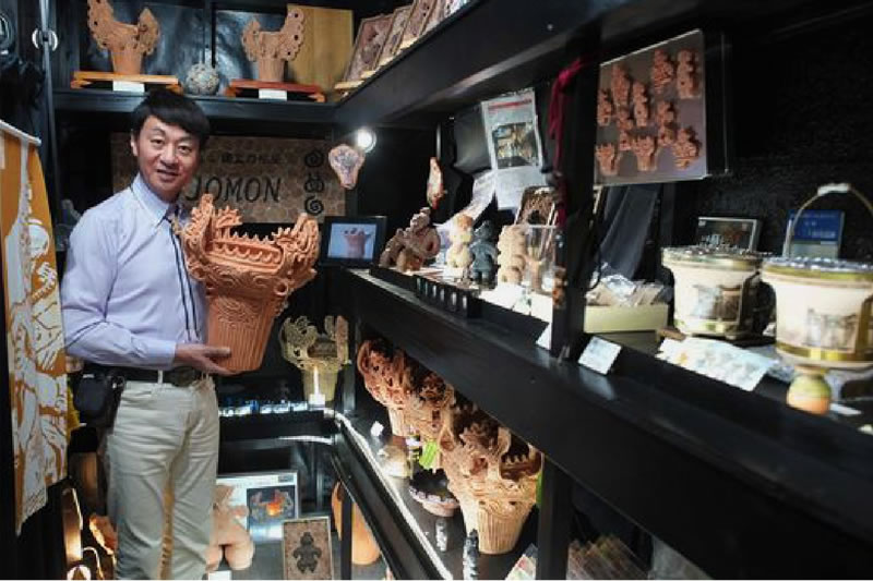 Image of representative Takao Koike holding a flame pottery replica in the gallery
